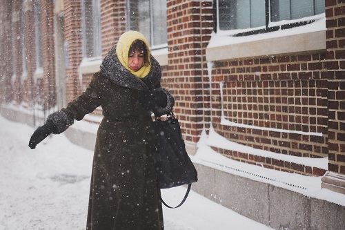 A woman trying not to fall on a snowy sidewalk