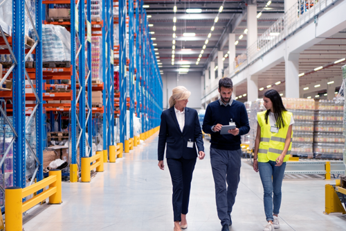 A warehouse manager and employees inspecting their building and inventory.