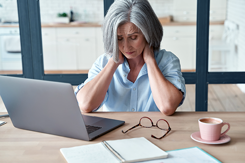 A woman working from home experiencing neck pain.