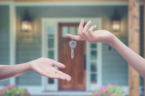 A landlord passing the key to a rental property to a tenant.